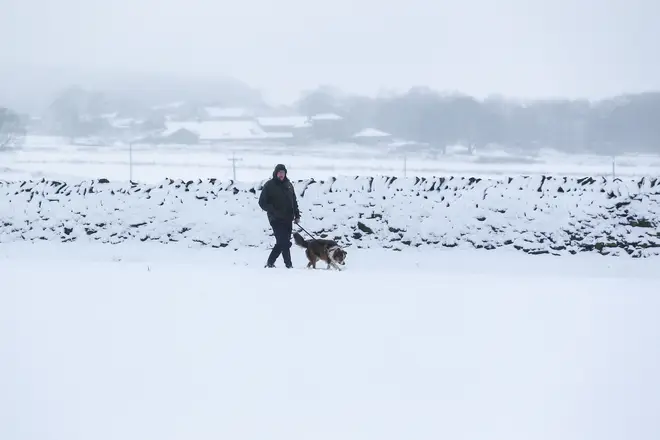 File photo: A man walks his dog across a snow-covered field in West Yorkshire