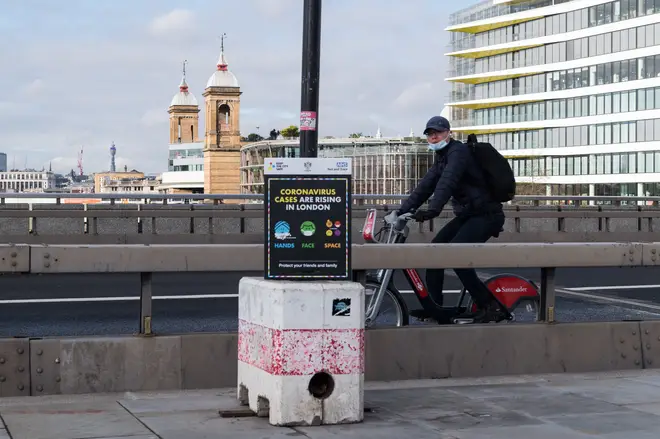 A cyclist rides past a coronavirus prevention poster on London Bridge as England remains under third lockdown