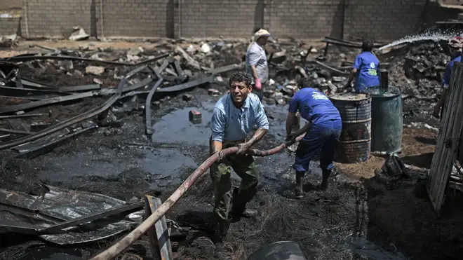 Workers use a water hose to put down a fire at a vehicle oil store hit by Saudi-led airstrikes in Sanaa, Yemen.