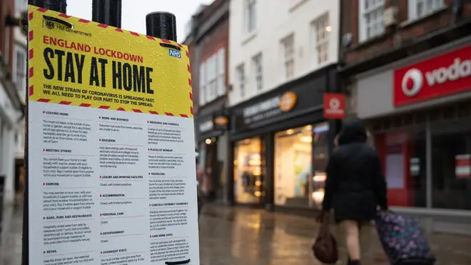 People walk past a 'Stay at Home' poster in a high street