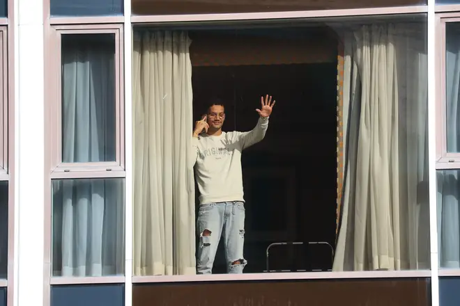 Roger Goncalves, who is from Brazil and travelled via Madrid to get to the UK, waves from the window of Radisson Blu Edwardian Hotel
