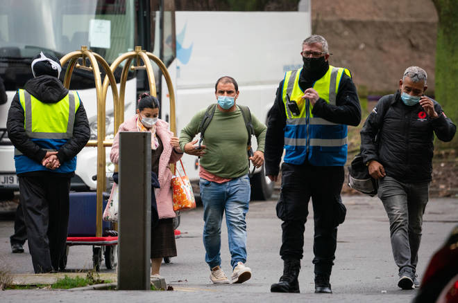 Security escort passengers as they arrive at a hotel near Heathrow Airport, London, to begin a 10 day quarantine period