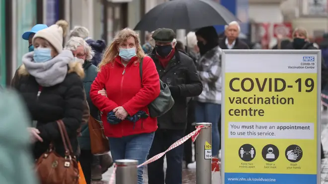 People queue in bad weather to enter a COVID-19 vaccination centre in Folkestone, Kent
