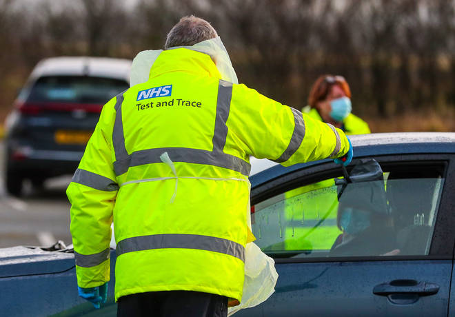 An NHS Test and Trace worker hands a person a test kit in a drive through testing centre in Southport, Lancashire