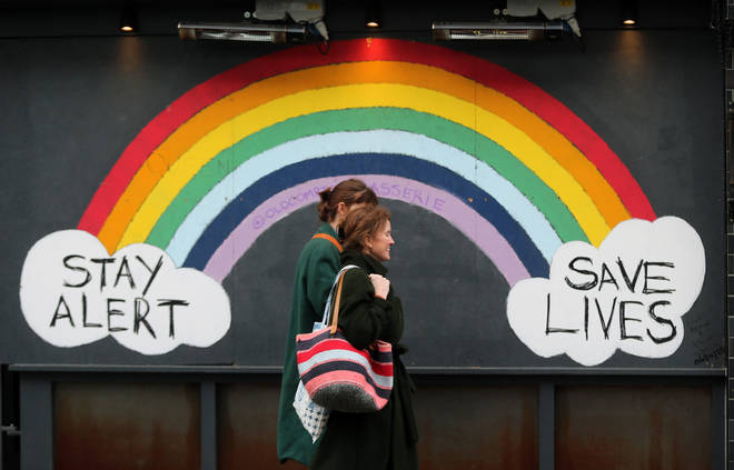Two women walk past graffiti with the message 'Stay alert, save lives' in London's Soho