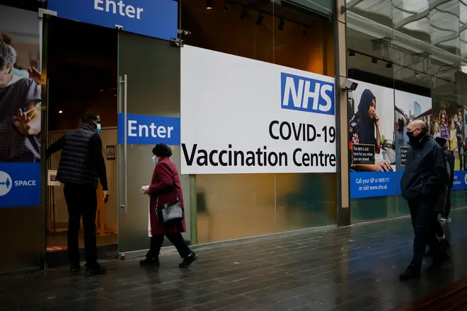 A member of staff greets people entering an NHS Covid-19 vaccination centre in east London