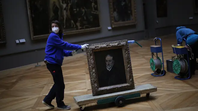 A worker transports the painting called Portrait of Antonio de Covarrubias y Leiva by Spanish painter El Greco in the Louvre museum in Paris