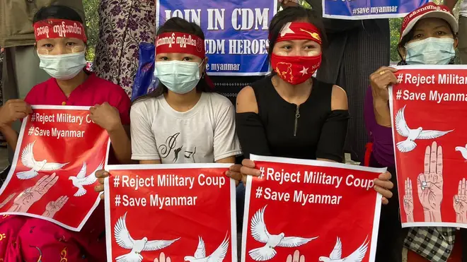 Anti-coup protesters hold posters that read “#Reject Military Coup #Save Myanmar” as they gather in Yangon on Monday
