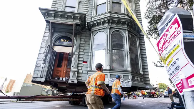 A Victorian house is moved through the streets