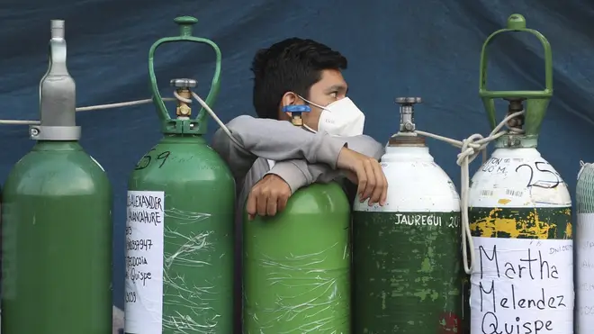 A youth rests on his empty oxygen cylinder waiting for a refill shop to open in Lima, Peru