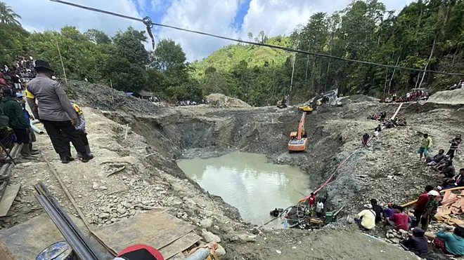 Rescue workers pump water out of the collapsed gold mine