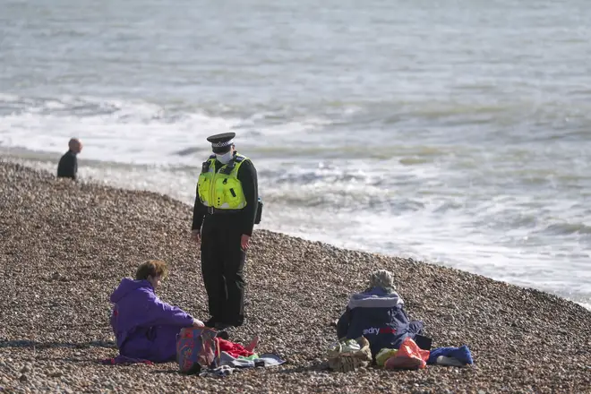 A community support officer speaks to people enjoying the sunshine on Brighton beach in Sussex on Sunday.