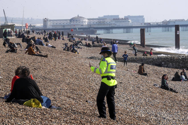 A community support officer speaks to people enjoying the sunshine on Brighton beach in Sussex on Sunday.