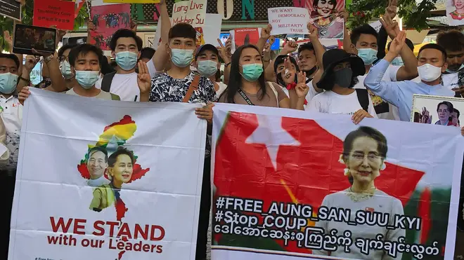 Migrant workers from Myanmar flash the three-finger protest gesture while they hold banners with images of deposed Myanmar leader Aung San Suu Kyi before participating in a march by Thai pro-democracy activists in Bangkok on Sunday