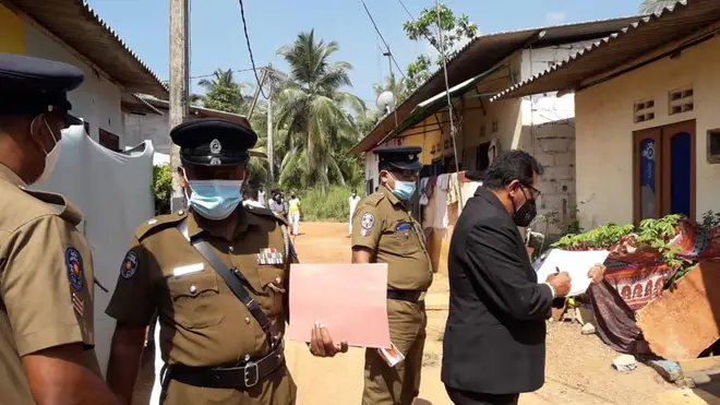 Police officers outside a house where a nine-year-old girl was canned to death in Delgoda, Sri Lanka