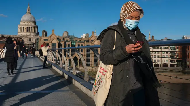 A pedestrian wearing a mask crosses the Millennium Bridge in London