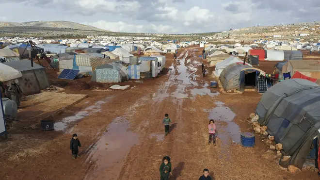 Syrian refugees walk through a camp for displaced muddied by recent rains near the village of Kafr Aruq, in Idlib province, Syria (Ghaith Alsayed/AP)