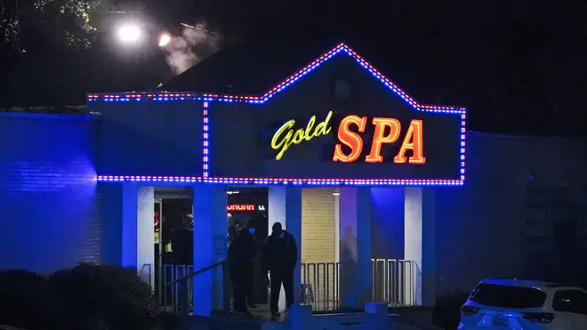 Law enforcement officials confer outside a massage parlor following a shooting