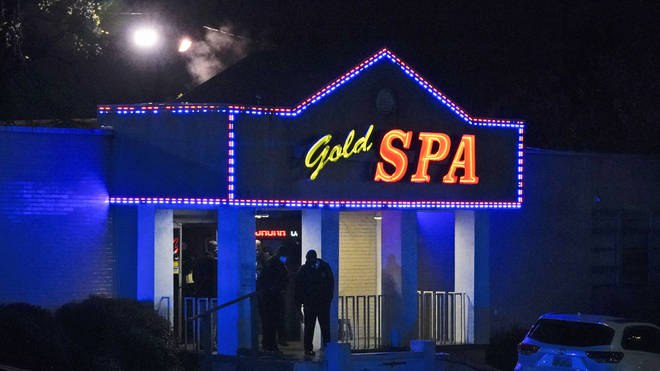 Law enforcement officials confer outside a massage parlor following a shooting