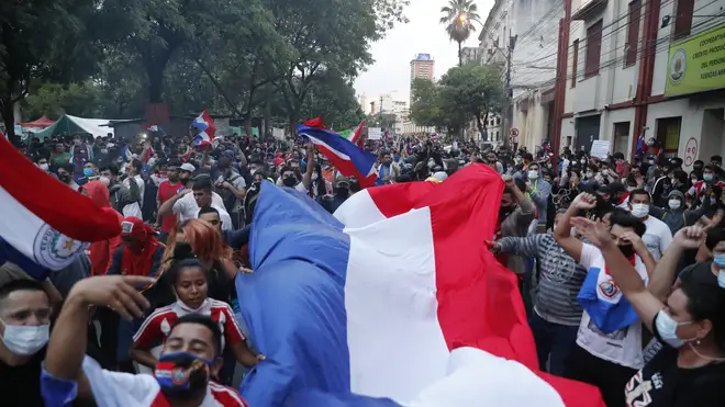 Demonstrators carry a Paraguayan flag during a protest after a failed impeachment of President Mario Abdo Benitez, in Asuncion, Paraguay (Jorge Saenz/AP)