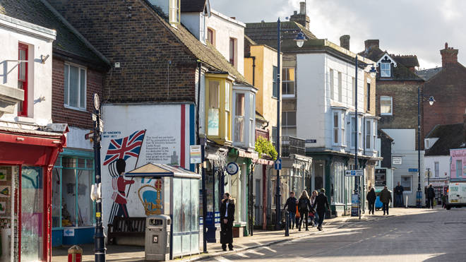 People walk past a parade of shops in Whitstable