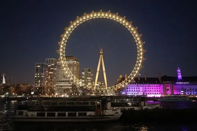 The London Eye in London is illuminated yellow during the National Day of Reflection.