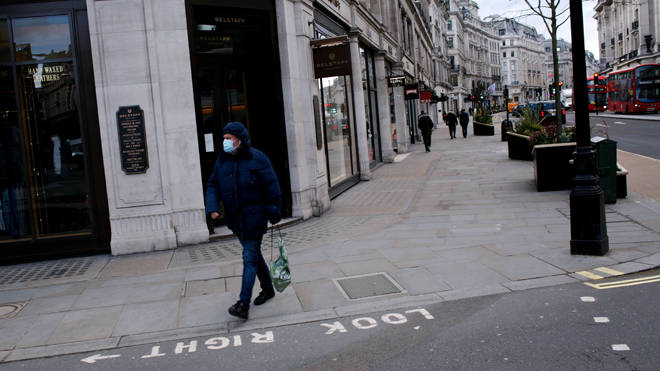 A man wearing a face mask walks along a near-deserted Regent Street in London