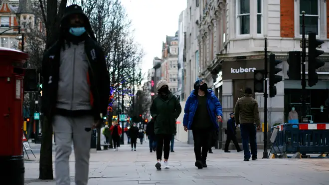 People wearing face masks walk along a near-deserted Oxford Street in London