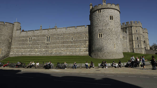 People sit in the sun outside Windsor Castle in Berkshire.