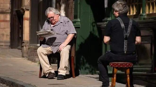 A man reads a newspaper in the sun in Central London