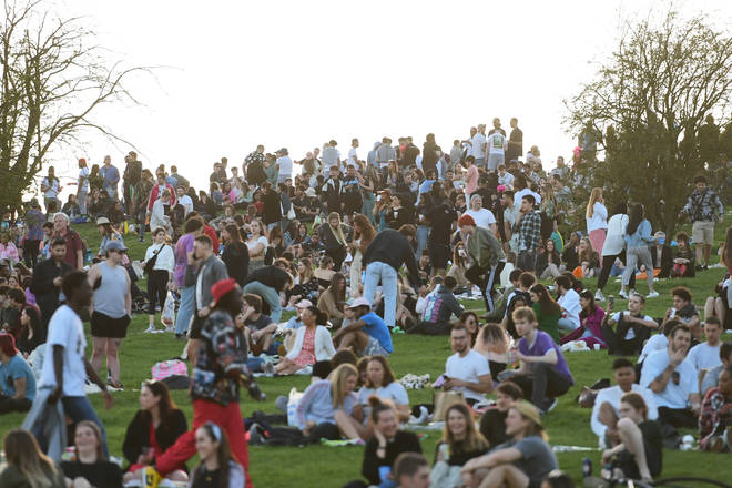 People enjoy the evening sunlight on Primrose Hill