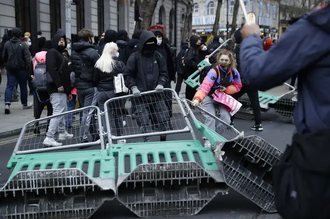 Demonstrators drag road works fences into the street during clashes with police.
