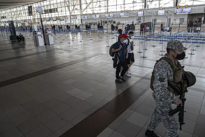 A soldier and a few passengers walk inside the deserted Santiago airport on Monday.