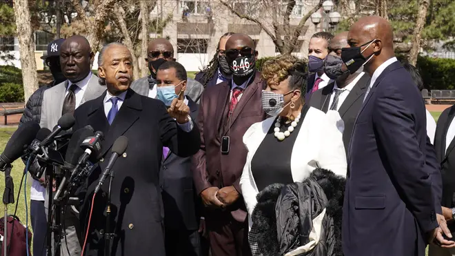Civil rights activist Rev Al Sharpton, centre, leads a prayer outside the Hennepin County Government Centre during lunch break.