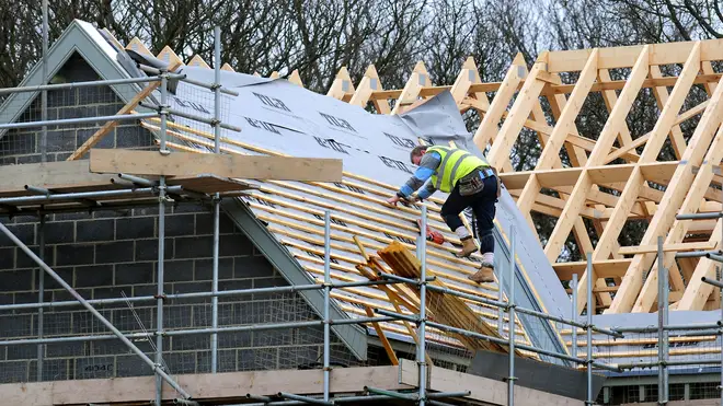 A roofer works on a new house building project