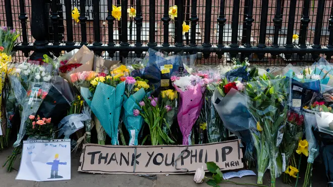 A bouquets of flowers with a note is seen outside Buckingham Palace