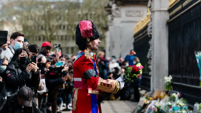 A man speaks and gestures as he brings flowers to Buckingham Palace