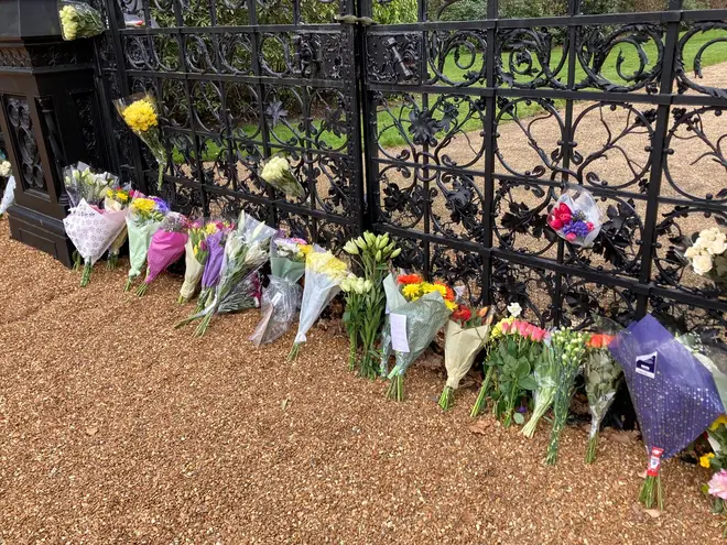 A row of bouquets leans against the gate outside the Sandringham Estate