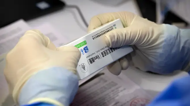A worker opens a package of coronavirus vaccine made by a Sinopharm subsidiary
