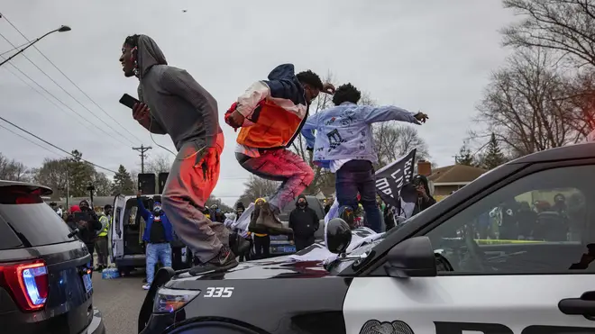 Men jump on the hood of a police car