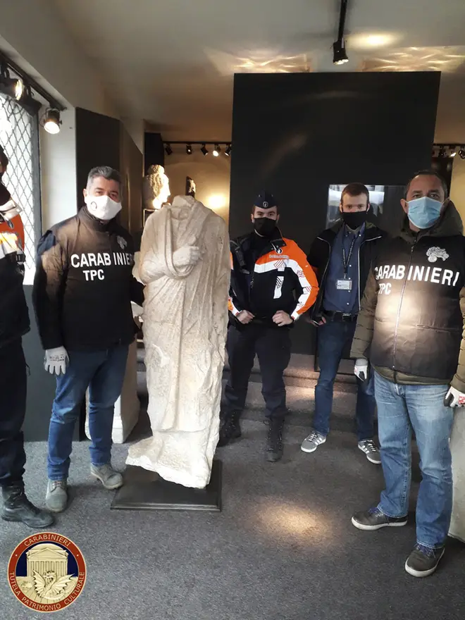 Carabinieri officers of the art squad’s archaeological unit pose with a headless Roman statue wearing a draped toga in Brussels