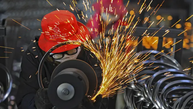 Workers wearing face masks polish bicycle wheel rims which causes sparks to fly