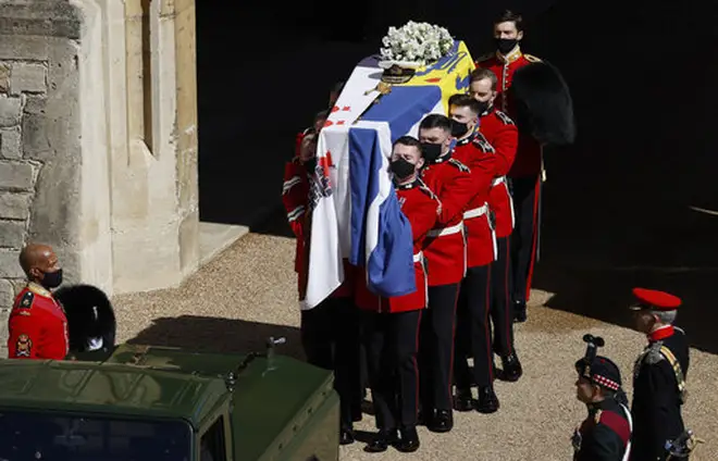 Members of the Queen's Company, 1st Battalion Grenadier Guards prepare to place the coffin onto the Land Rover