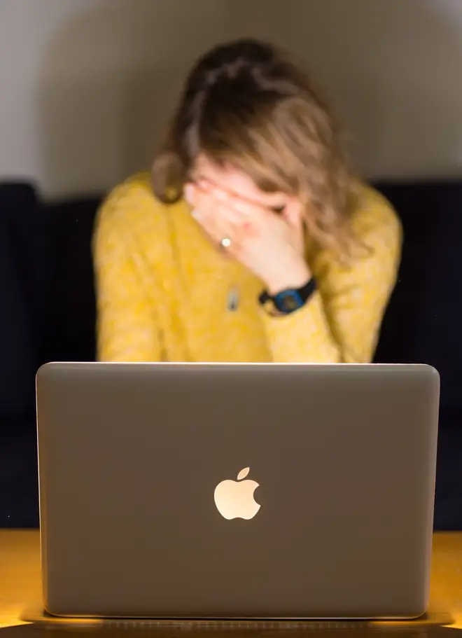 A woman looking stressed as she uses a laptop