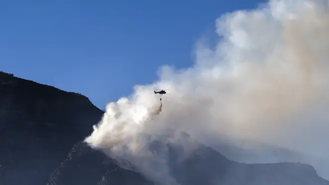 A South African military helicopter drops water on the top of Table Mountain in Cape Town