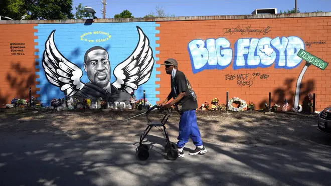 A man walks past a mural in the Houston neighbourhood where George Floyd grew up
