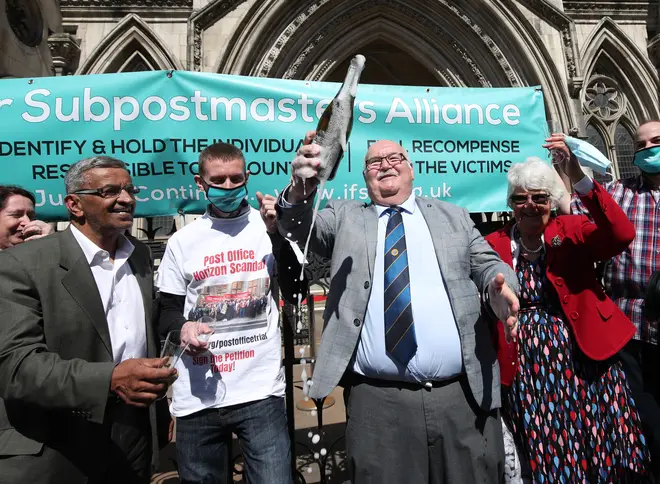 Former post office worker Tom Hedges (centre) pops a bottle champagne in celebration after his conviction was overturned.