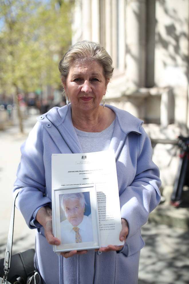 Karen Wilson, widow of postmaster Julian Wilson, who died in 2016, holds a photograph of her husband after his conviction was overturned.