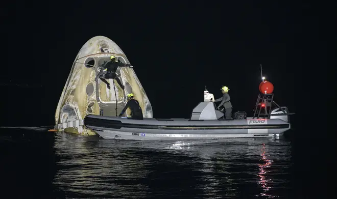 Support teams work around the SpaceX Crew Dragon Resilience spacecraft shortly after it landed.