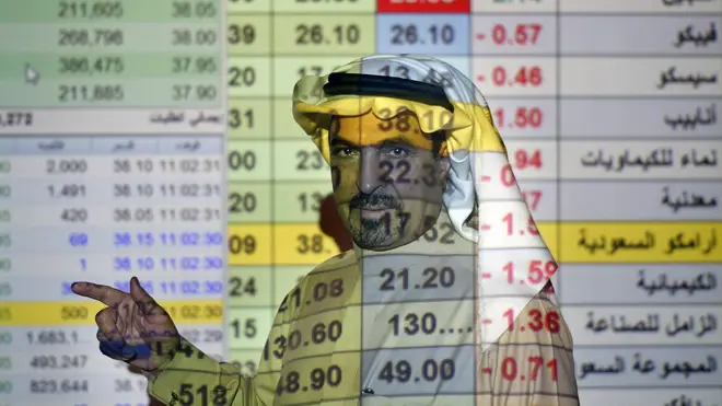 A trader in front of a screen displaying Saudi stock market values